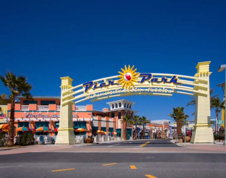 Pier Park entrance arch at Panama City Beach, Florida, with colorful shops and palm trees under a clear blue sky